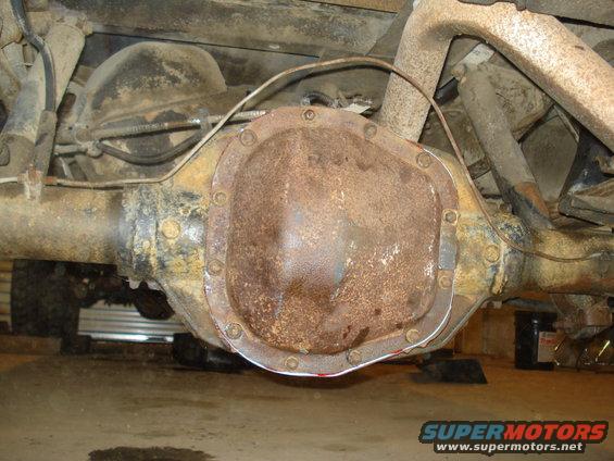 Rusty rear differential with bolts and brake lines visible
