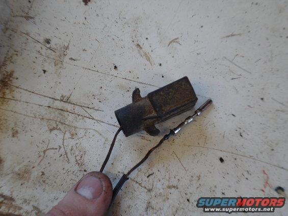 Rusty electrical connector with two wires attached, held by a thumb