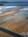 2007 Dodge Caliber - A vibrant hot spring displays a spectrum of colors, with a calm blue body of water and distant hills in the background.