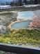 2007 Dodge Caliber - Geothermal pools with colorful mineral deposits and yellow wildflowers, with a wooden boardwalk in the background.