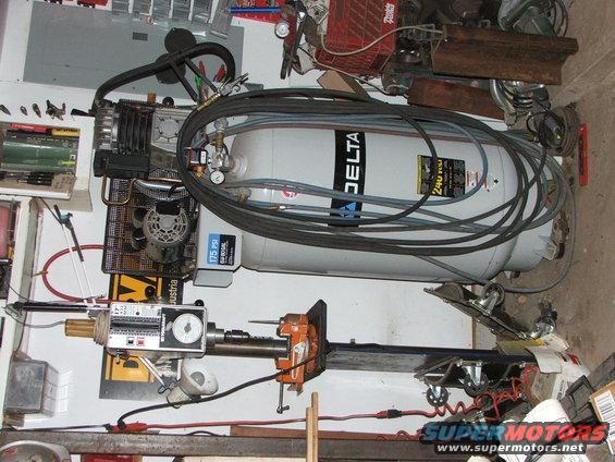 Air compressor with Delta logo and a drill press in a cluttered garage