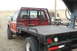1994 GMC Sierra 3500 - The rear passenger side of a red flatbed truck is shown, a custom headache rack and a gooseneck hitch.