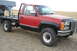 1994 GMC Sierra 3500 - This red 1994 GMC Sierra 3500 pickup features a flatbed conversion and a gooseneck hitch, seen here from a three-quarter front perspective.