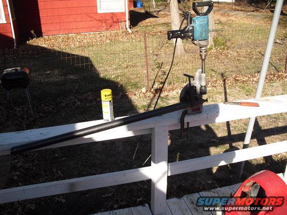 Jackhammer clamped to a pipe on a railing, with a can of spray lubricant nearby