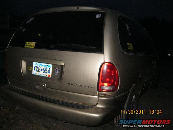 Rear view of a gold Dodge Grand Caravan with a Minnesota license plate XXG-654. "TOWN & COUNTRY" is visible on the tailgate