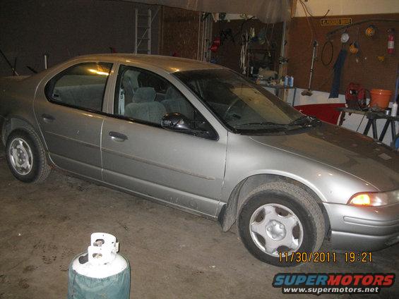 Silver sedan parked inside a garage. A propane tank is in the foreground