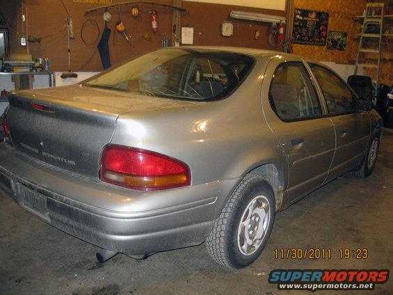 Silver sedan rear quarter view, showing a dented bumper and a 'STRATUS' badge on the trunk