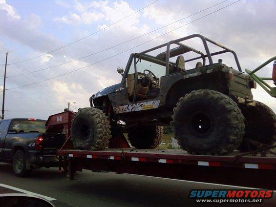 Modified Jeep Wrangler on a flatbed trailer being towed by a pickup truck