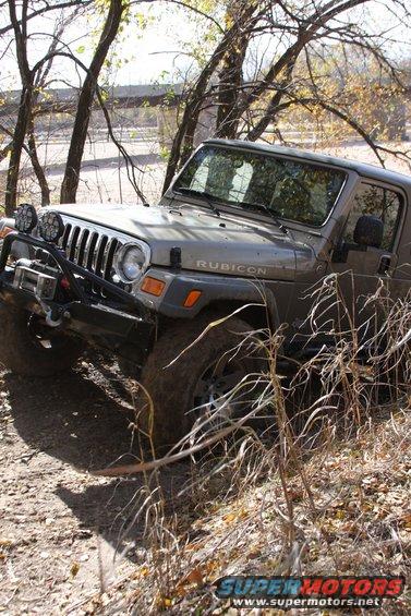 2005 Jeep Wrangler Rubicon on a dirt trail with trees and dry grass