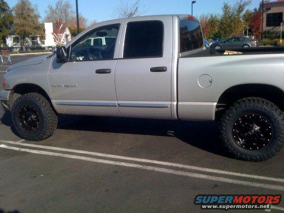 Silver Dodge Ram 1500 pickup truck with aftermarket wheels and tires, parked in a lot