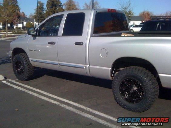 Silver pickup truck with black rims and lifted suspension, seen from the side