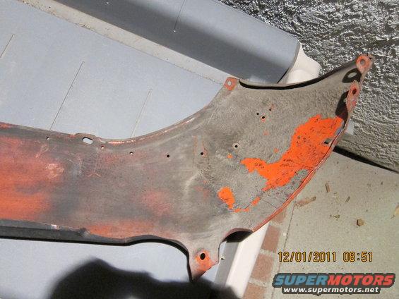 Orange painted car fender section with mounting holes