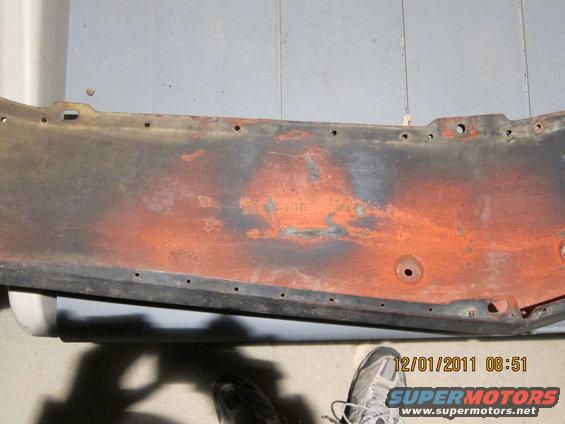 Rusted metal panel with orange undercoat, black trim, and mounting holes