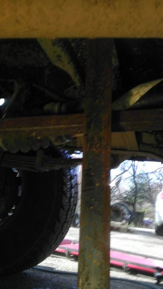 Close-up of a rusty metal suspension component and tire