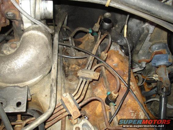 Close-up of engine compartment showing rusted metal, fuel lines, and hoses