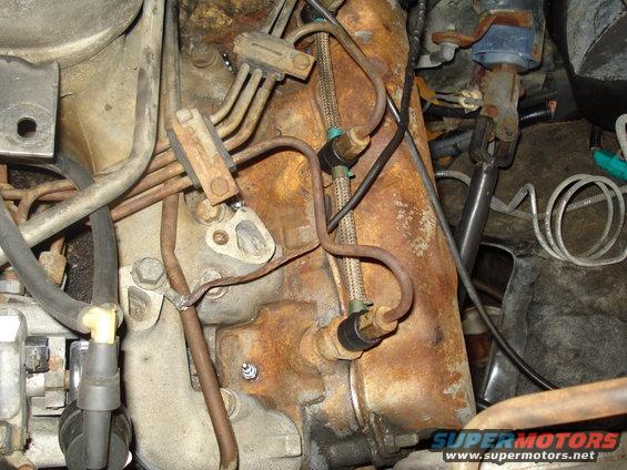 Close-up of engine bay showing fuel lines and rusty components