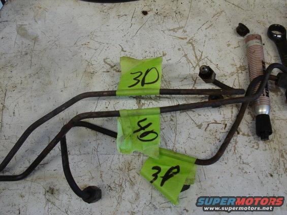 Several metal brake lines with green tape labeled 3D, 4D, and 3P on a workbench