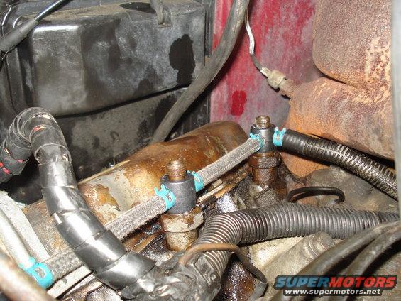 Engine bay with fuel lines and wiring harness. Red painted metal in background