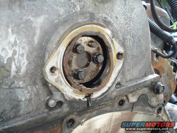 Close-up of engine timing cover seal area with bolts