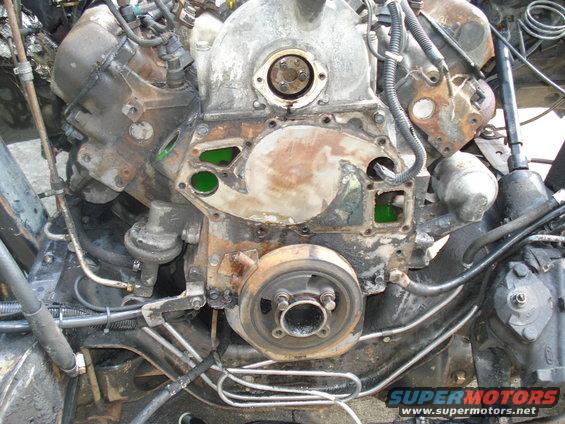 Close-up of an engine block showing coolant passages with green fluid and a crankshaft pulley