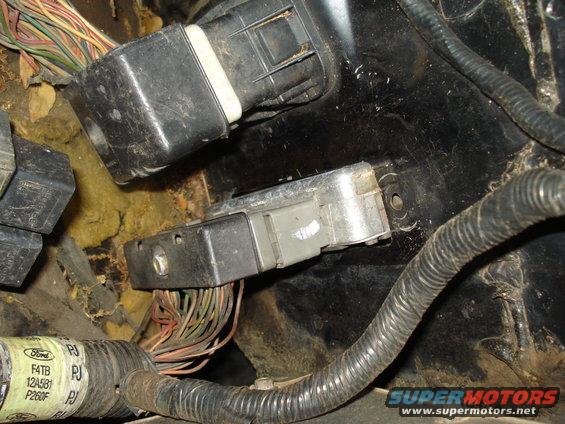 Engine control module with wiring harness and connectors, some text visible on a cable