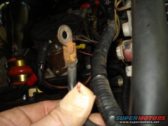 Close-up of a corroded battery terminal with wiring and tape