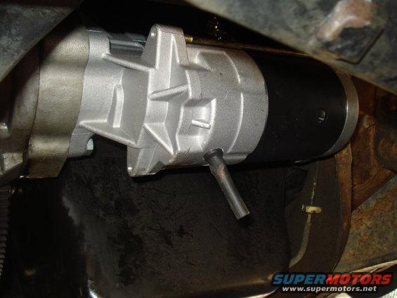 Close-up of a silver and black starter motor mounted under a vehicle