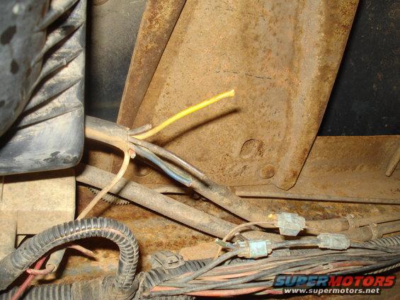 Close-up of a rusty metal bracket with a yellow wire and other electrical connectors