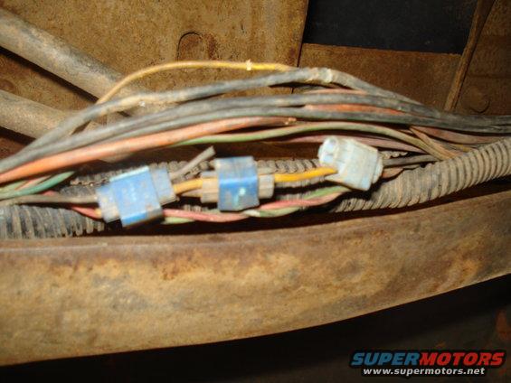 Vehicle wiring harness with blue and white connectors, showing rust on surrounding metal
