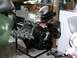 1996 Ford Bronco - A V8 engine, fitted with a supercharger and chrome headers, is displayed on a stand in a garage setting.