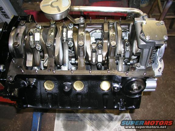 Engine block with crankshaft and connecting rods visible, brass plugs on the side