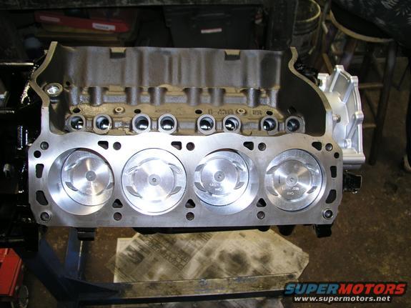 Engine block with four pistons visible, part number visible on block