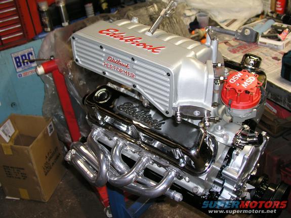 Silver Edelbrock Performer intake manifold and chrome valve covers on a V8 engine with headers