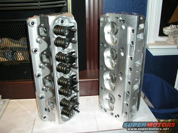 Two aluminum engine cylinder heads with springs and valves visible
