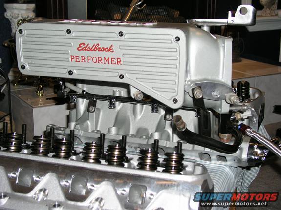 Silver Edelbrock Performer intake manifold on an engine block with visible valve springs