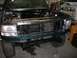 1996 Ford Bronco - The front end of a green SUV is shown with the hood open, revealing the engine compartment and radiator.
