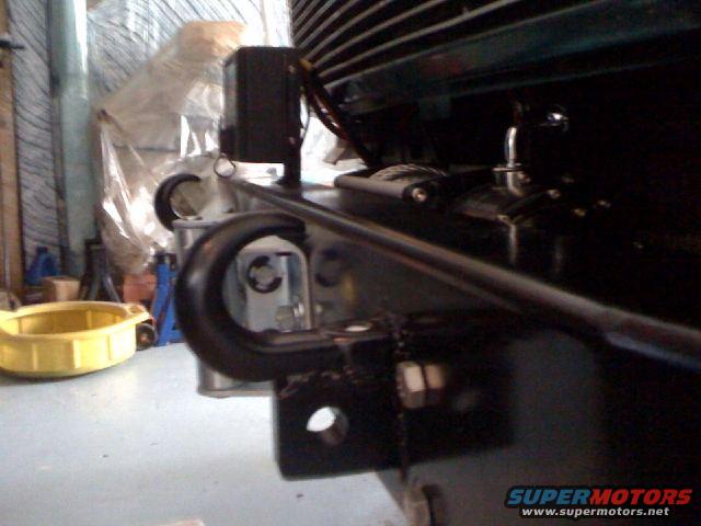 Black tow hook attached to vehicle frame with visible bolts and nuts
