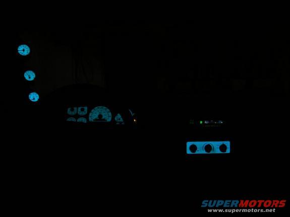 Car interior at night showing glowing blue gauges and climate controls