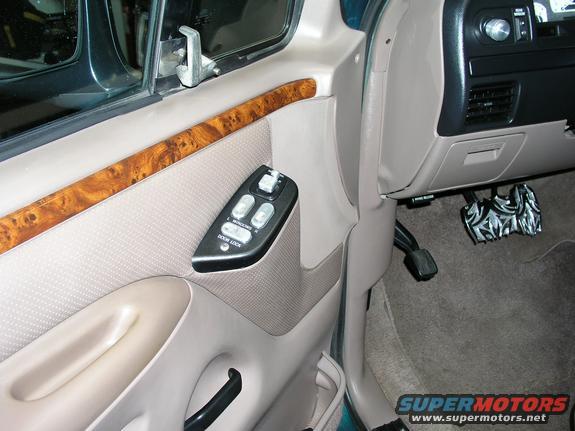 1996 Ford Bronco interior door panel with wood trim, power window controls, and dashboard section with pedals