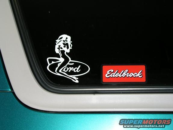 Car window with a white Ford logo sticker a pin-up girl and a red Edelbrock sticker