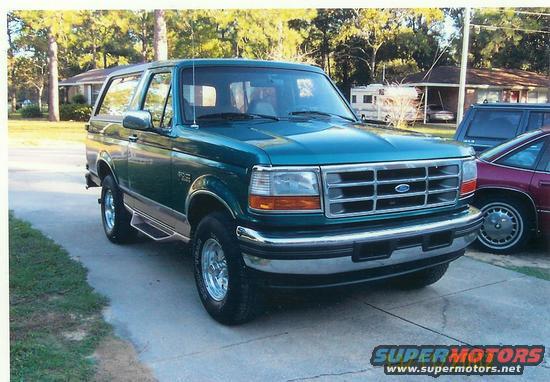 Green 1996 Ford Bronco parked on driveway with another car and RV in background