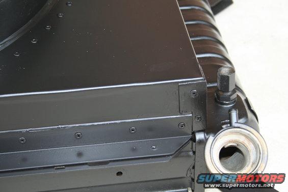 Black radiator fan shroud with visible screws and hose fittings