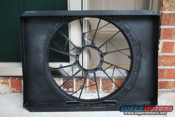 Black plastic radiator fan shroud with a circular opening and internal bracing