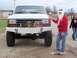1989 Ford Bronco - A white Ford truck is parked with toys on its bumper, while a man dressed as Santa Claus stands beside it.