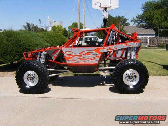 Custom off-road buggy with red roll cage and silver/orange flame graphics on the side panels