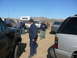 1988 Ford Bronco - Several vehicles and people are gathered in a dusty, outdoor location under a clear blue sky.