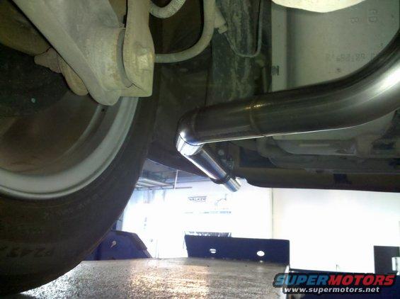 Underside view of a car's dual exhaust system with a tire visible