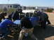 1988 Ford Bronco - A crew attends to a buggy during an off-road event, with an RV in the background.