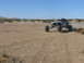 1988 Ford Bronco - Off-road buggy navigates a dusty desert terrain under a clear blue sky.