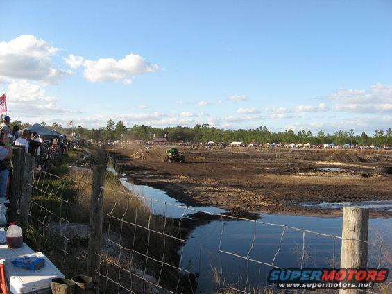 Mud bogging event with spectators watching a tractor in the distance